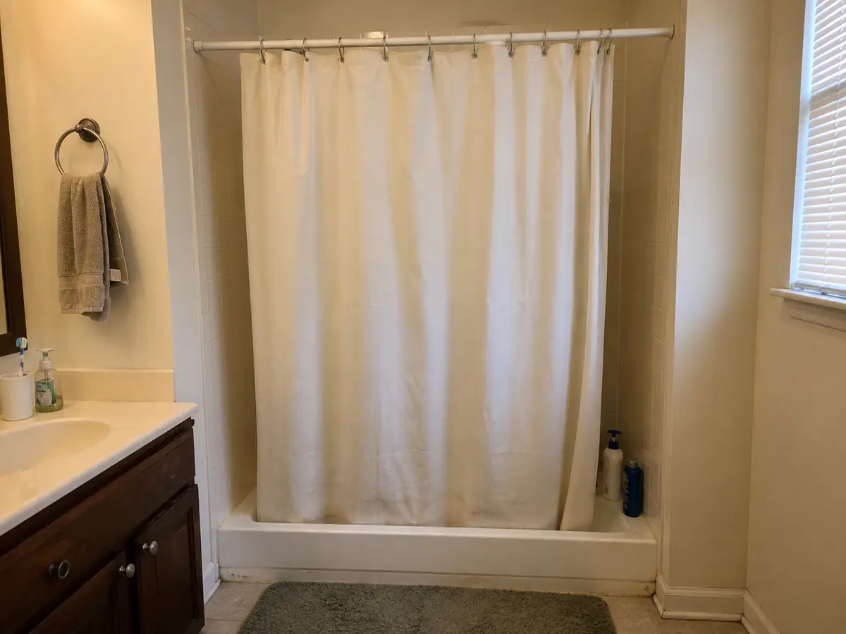 Bathroom before the shower enclosure update, with a fabric shower curtain