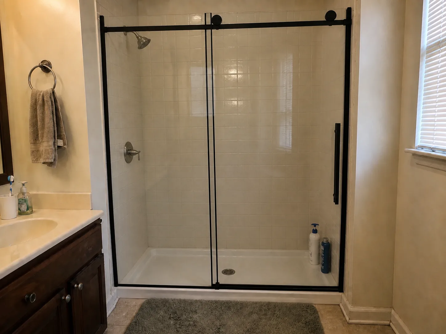 Bathroom after the update, with a black framed sliding glass shower door